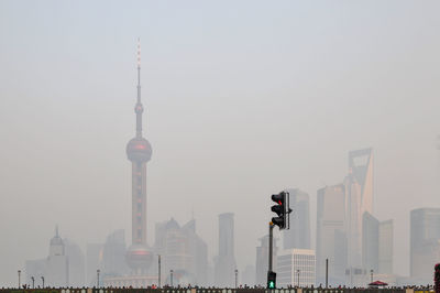 Communications tower in city against sky