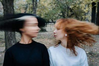 Lesbian couple shaking heads while standing against trees in park