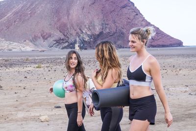 Smiling women carrying exercising mat on field