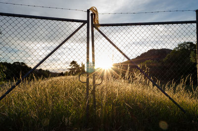 Fence on field against sky during sunset