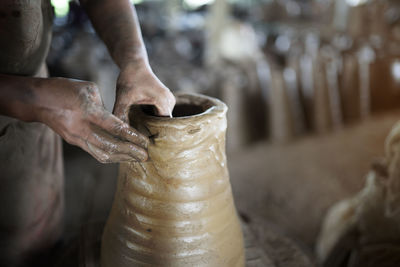 Cropped hands of potter making pot at workshop