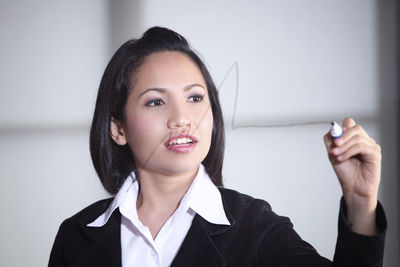 Businesswoman writing on glass board