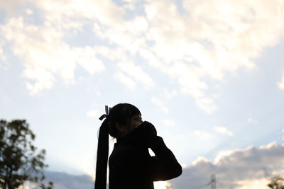 Low angle portrait of boy standing against sky