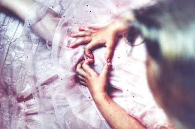 High angle view of girl making heart shape on bed