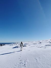 Woman on snowcapped mountain against clear blue sky