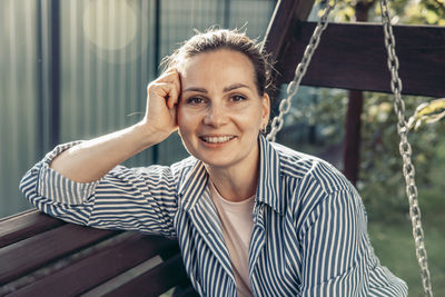 Portrait of young woman sitting on swing at playground