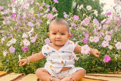 Portrait of cute baby boy sitting on field