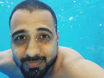 Close-up portrait of shirtless man swimming in pool