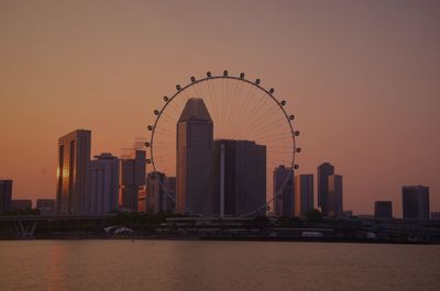 View of ferris wheel against cityscape at sunset