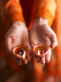 Close-up of hand holding illuminated diyas