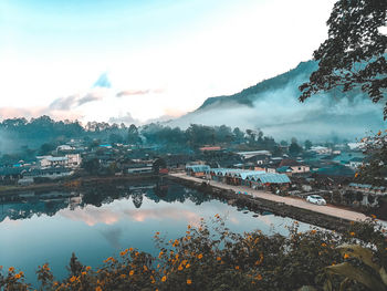 Scenic view of lake by townscape against sky