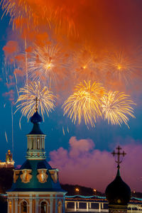 Firework display in city against sky at night