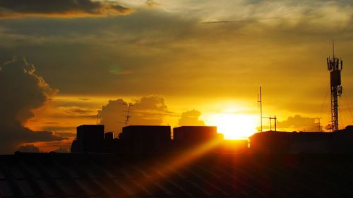 Silhouette buildings against dramatic sky during sunset