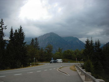 Road by trees against sky