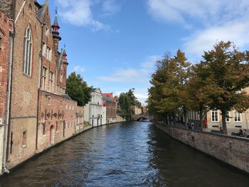 Canal amidst buildings in city against sky