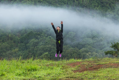 Rear view of young woman moving down on grassy hill