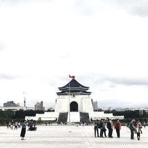 People at town square against cloudy sky