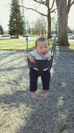 Portrait of cute baby boy enjoying swing in park