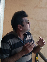 Portrait of man smoking cigarette against wall