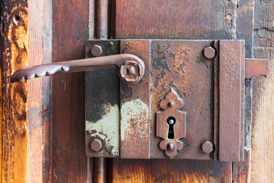 Close-up of an old decorated door with corroded and rusty metal lock, door handle