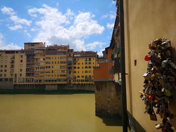 Buildings by canal against sky in city