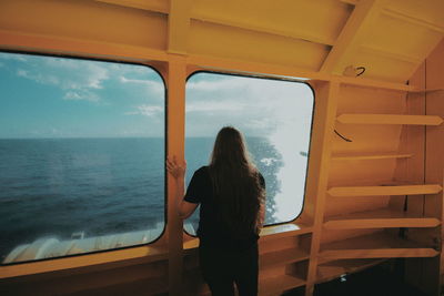 Rear view of woman looking through boat window