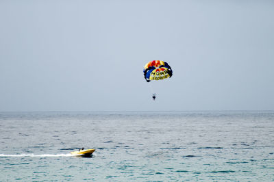 Low angle view of person paragliding over sea against clear sky