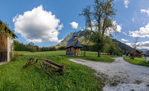 House on field by trees against sky