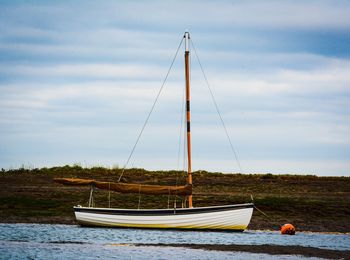 Sailboat moored on sea against sky