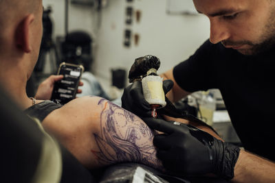 Male tattoo artist draws on the client skin, process of creating tattoo art	
