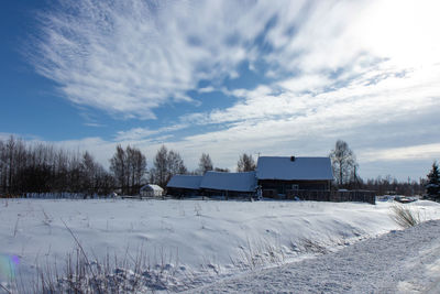 Houses on field against sky during winter