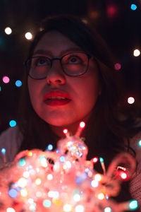 Close-up of young woman with illuminated lights at home