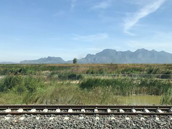 Railroad track amidst field against sky