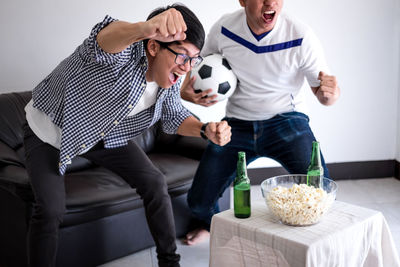 Friends dancing while watching sports on tv at home