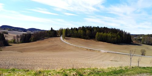 Empty road along trees and landscape against sky