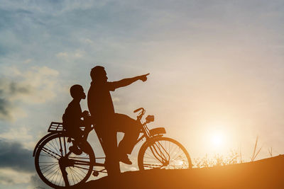 Silhouette man riding bicycle against sky during sunset