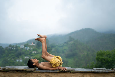 A young indian cute kid doing yoga in the mountains,wearing a dhoti