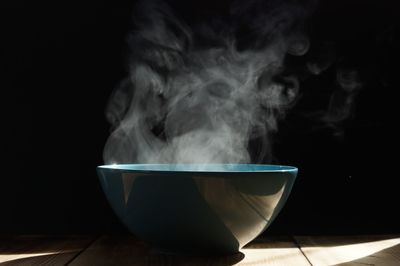 Close-up of smoke emitting from bowl on table