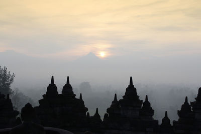 Silhouette borobudur temple with the mysteries forest surrounding during sunrise, yogyakarta