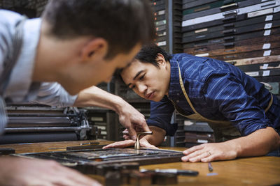 Close-up of workers working on letterpress on workbench