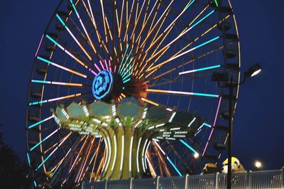 Low angle view of illuminated ferris wheel against sky at night