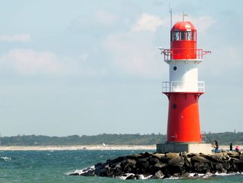 Lighthouse by sea against sky
