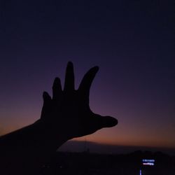 Silhouette person hand against sky during sunset