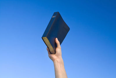 Close-up of hand holding umbrella against clear blue sky