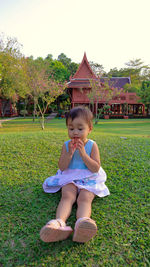 Girl looking away while sitting on field