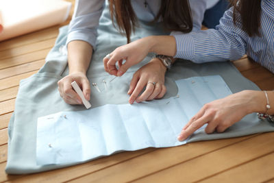 Hands of two cutters work with  pattern, concept of sewing business, small business and creativity.