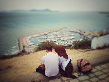 Rear view of couple sitting on beach