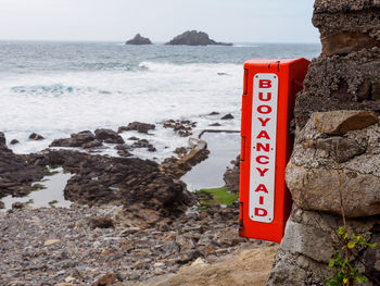 Information sign on rock by sea against sky