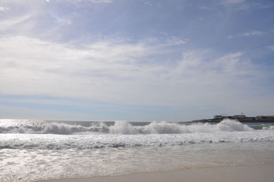 Waves splashing on shore against sky