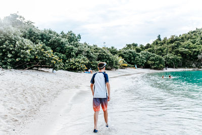 Rear view of man standing on beach against sky